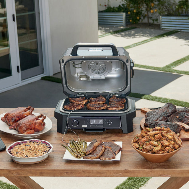 Ninja OG853A XL outdoor grill on a table with the lid open