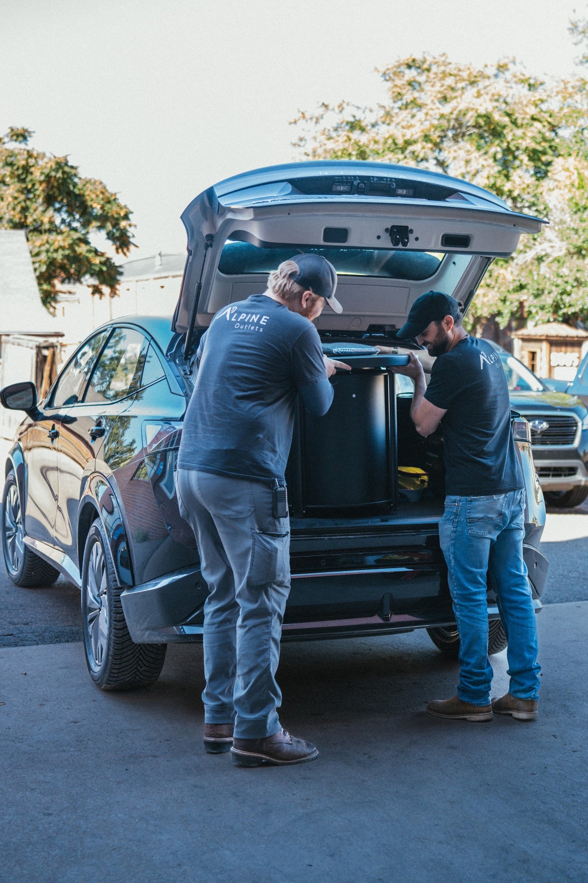 Two Alpine Outlets employees loading a customer's purchase into an SUV