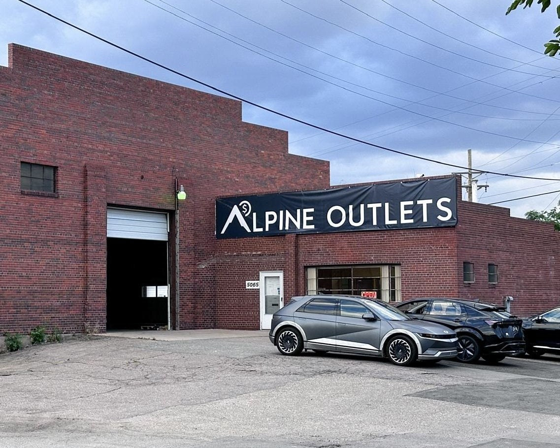 Alpine Outlets Denver at 5065 Colorado Blvd: a red brick warehouse with the Alpine Outlets banner over the front door